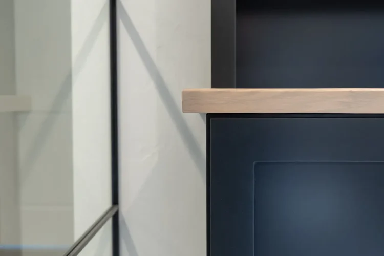 Close up of custom office shelves showing Tricorn Black painted cabinets with Pampas stained solid maple shelves and top